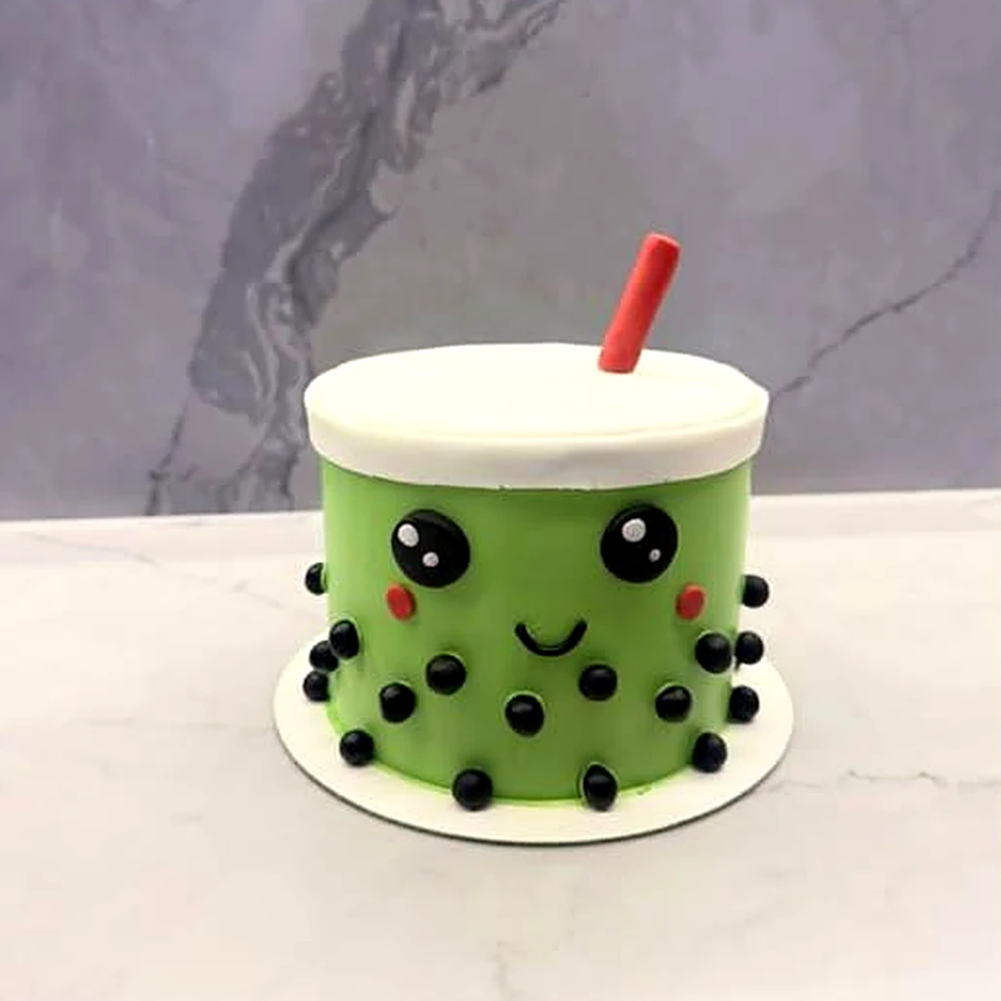 Green matcha bubble tea cake with a smiling face and red straw