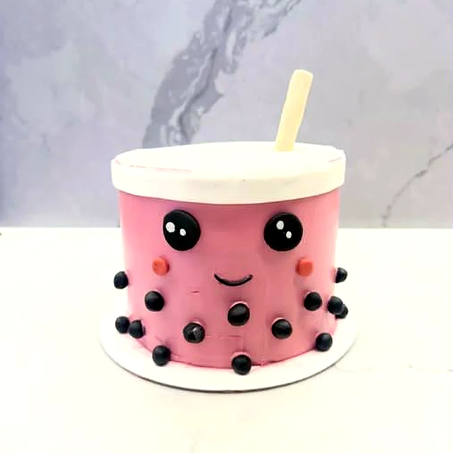 Pink bubble tea cake with a smiling face, pearl dots and a straw