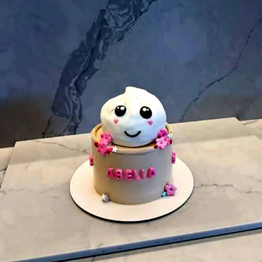 Small cake topped with a smiling steamed bun and pink flowers