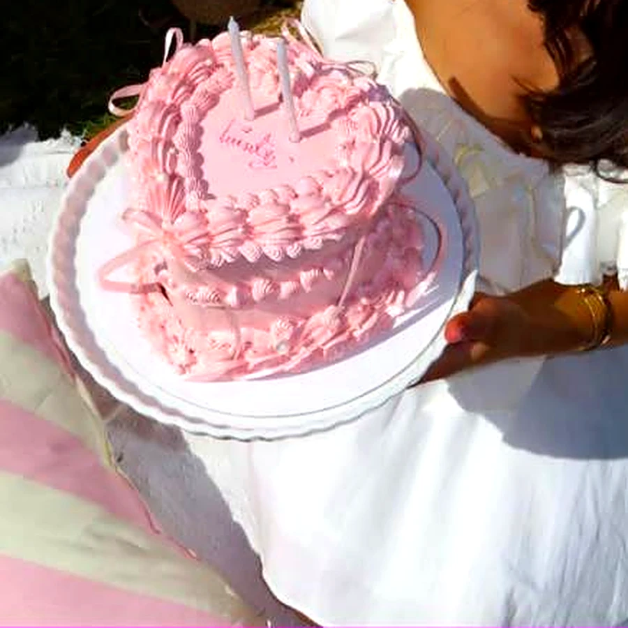 Pink heart-shaped vintage cake with ruffled piping and ribbons