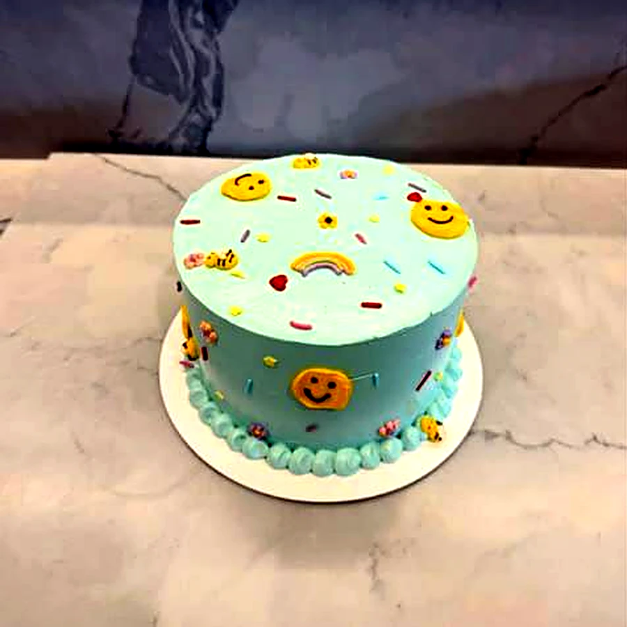 Mint buttercream cake with smiley faces, a rainbow and sprinkles